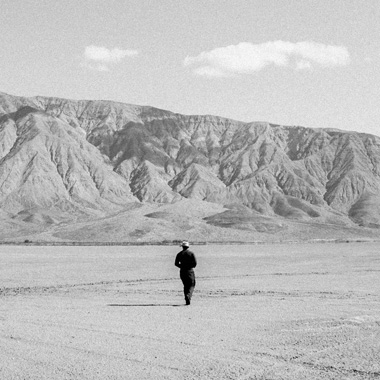 A man walking across a dry lake bed